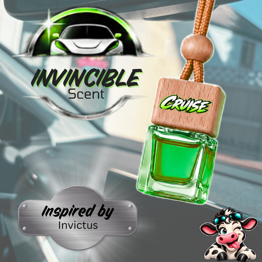 A green glass car air freshener bottle with a wooden label reading 'CRUISE' hangs from a brown cord. The background shows a blurred car interior with 'INVINCIBLE Scent' branding and 'Inspired by Invictus' text.