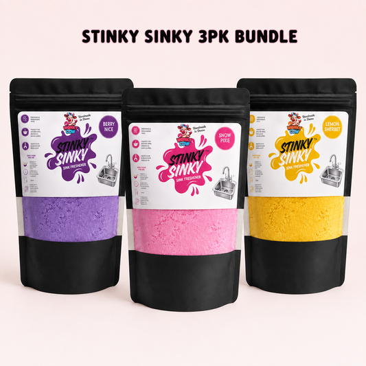 Three stand-up pouches of Stinky Sinky odor absorber in a 3-pack bundle, shown against a pale pink background with the text 'STINKY SINKY 3PK BUNDLE' at the top. The pouches are black with a clear window revealing purple, pink, and yellow powders.